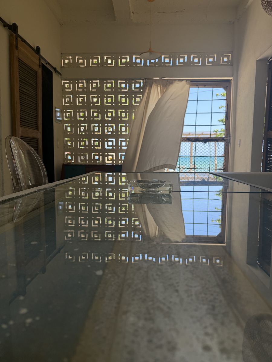 Mesa de vidrio que refleja la celosía y el mar